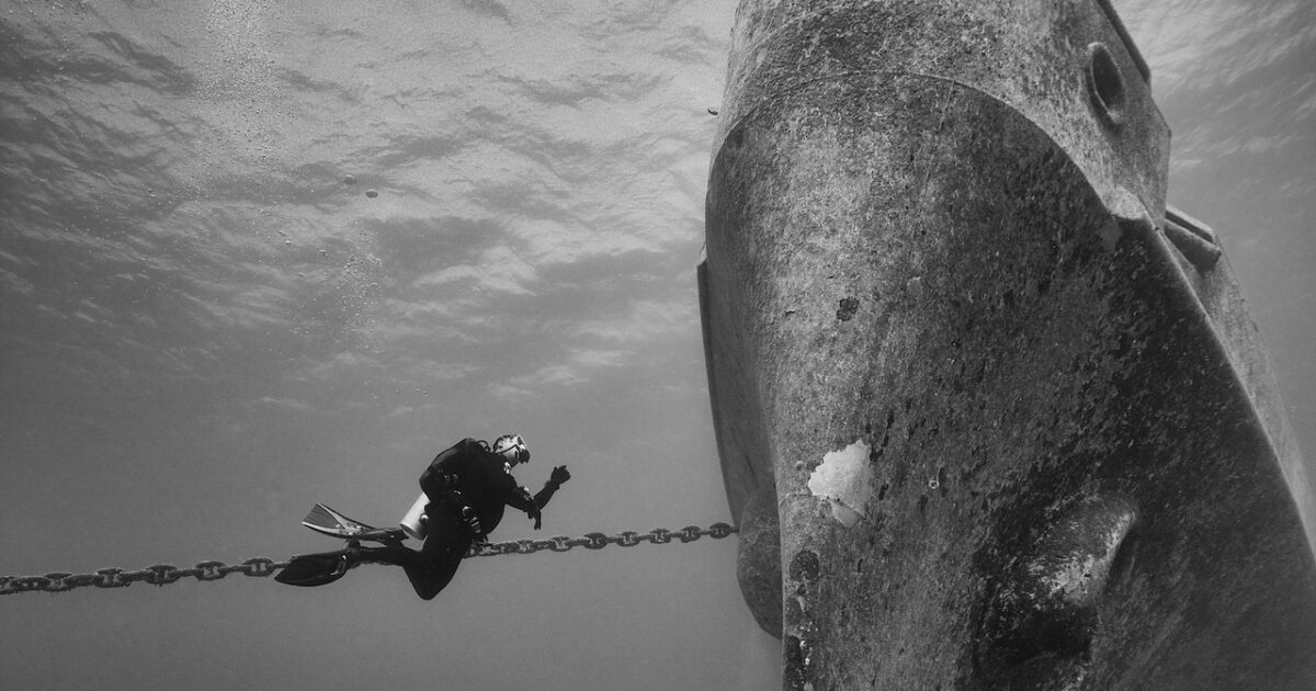 diver next to ship, underwater
